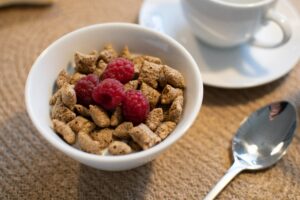 bowl of cereal with raspberries. cereal is one of the best meal train ideas for new mom