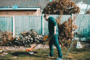 Person using an electric trimmer in their yard. Helping with housework and chores makes for great gifts for friend with broken arm