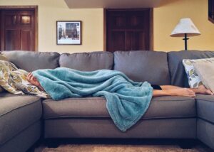person laying on a couch covered in a blanket