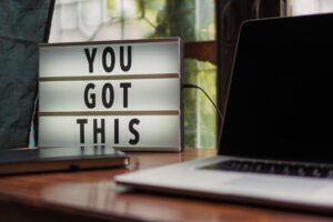 next to a laptop on a home desk sits a small reader board reading, "You Got This"