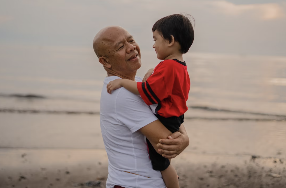 man holding a boy in his arms at the beach