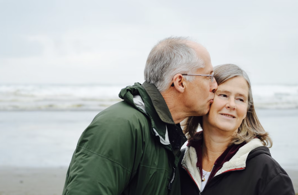 man kissing his wife on the cheek at the beach