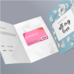 An open greeting card shows a printed message and affixed plastic Give InKind Visa Gift Card. Beside that is a closed greeting card showing the front, which reads, "Sending you all my love" This option will soon be available for both visa mastercard gift card