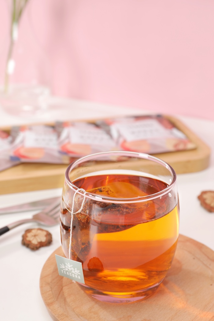 hot tea in a clear cup with a row of packaged tea bags in the background. gifts for friend with new job