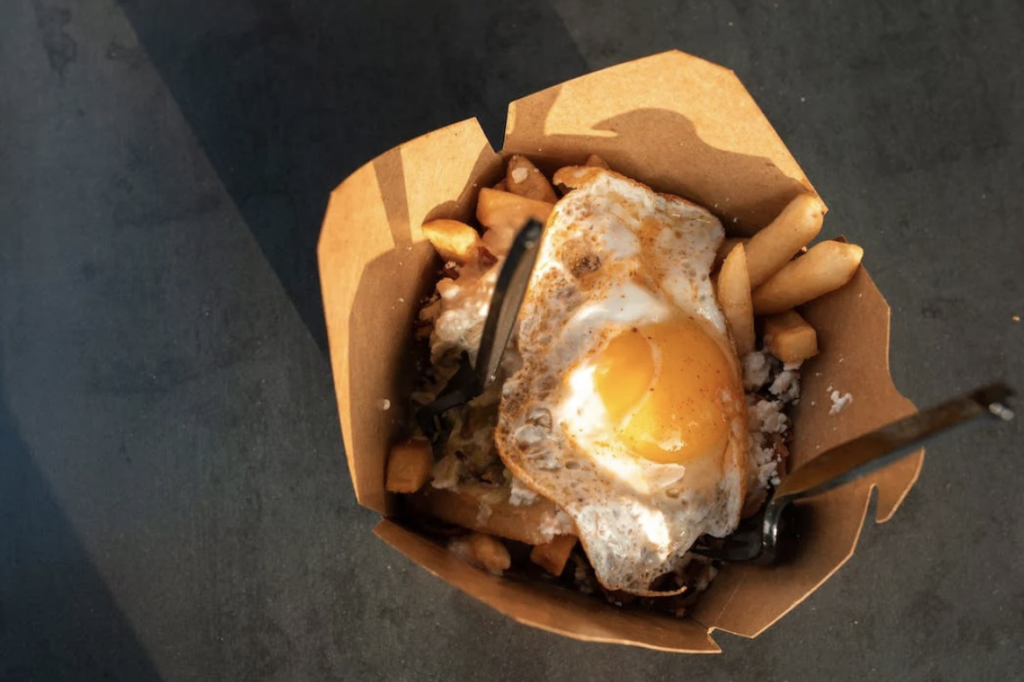 Takeout container of french fries topped with a fried egg