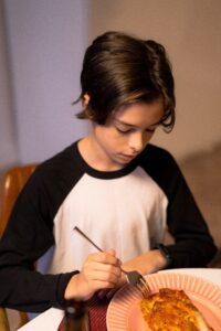 young person eating lasagna. a classic of meal train food ideas