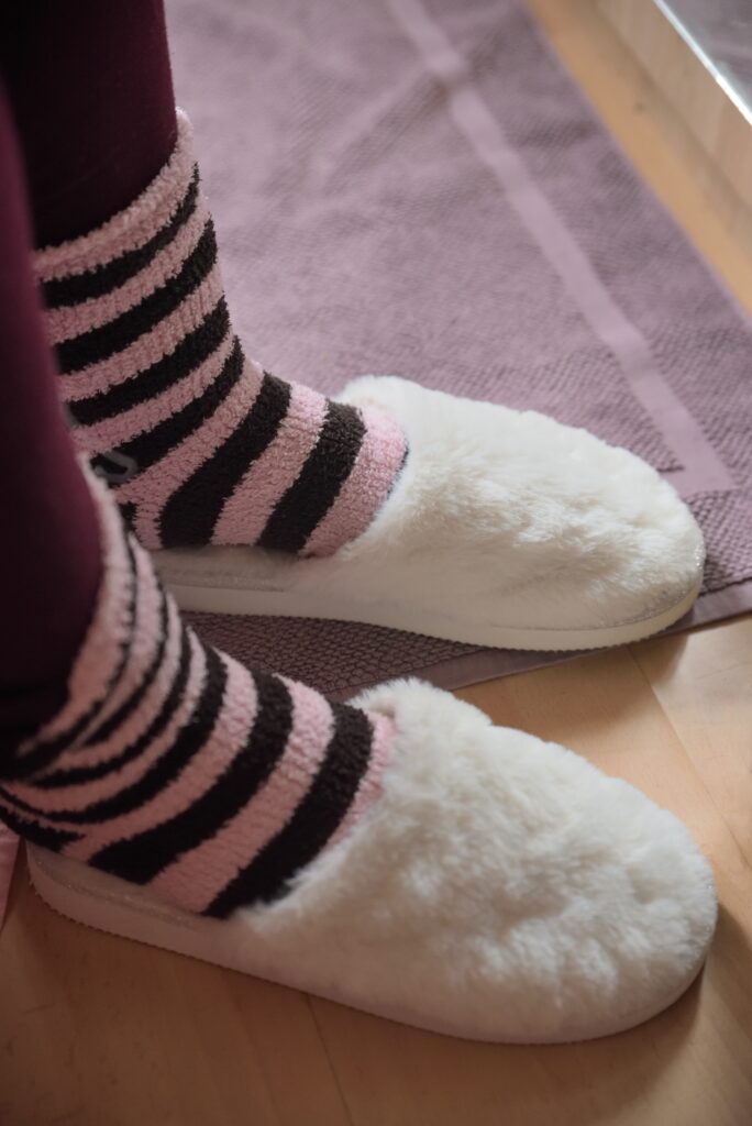 feet wearing fuzzy socks are slipped into fluffy slippers